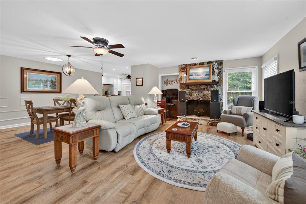 A living room features a stone fireplace, light-colored furniture, and wood-look flooring — 8 MIMOSA TRAIL, ORMOND BEACH, FL