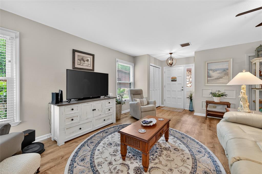 A living room features light-colored walls, wood-look flooring, a white media console, and a rug — 8 MIMOSA TRAIL, ORMOND BEACH, FL