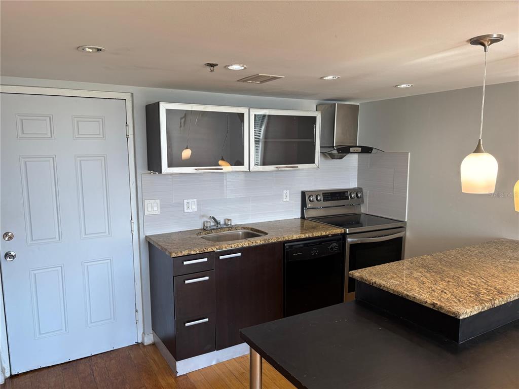 A kitchen features dark wood cabinets, granite countertops, stainless steel appliances, and a breakfast bar — 701 S MADISON AVENUE UNIT 315, CLEARWATER, FL