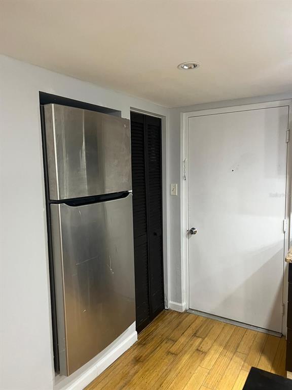 A stainless steel refrigerator stands next to a black louvered closet door and white door — 701 S MADISON AVENUE UNIT 315, CLEARWATER, FL