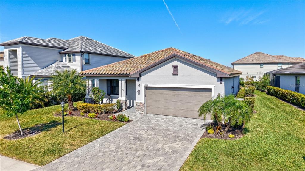 A single-story house with a paved driveway, a two-car garage, and a tiled roof — 15531 ISLANDWALK AVENUE, LAKEWOOD RANCH, FL