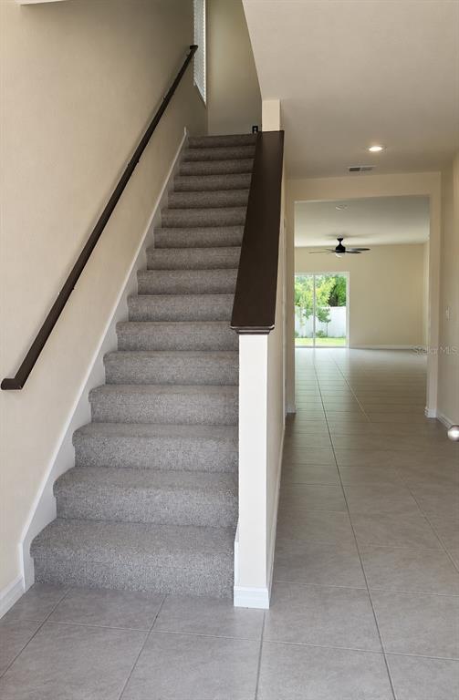 A carpeted staircase with a dark wood handrail leads to an upper level — 2450 TALONCREST COURT, EAGLE LAKE, FL