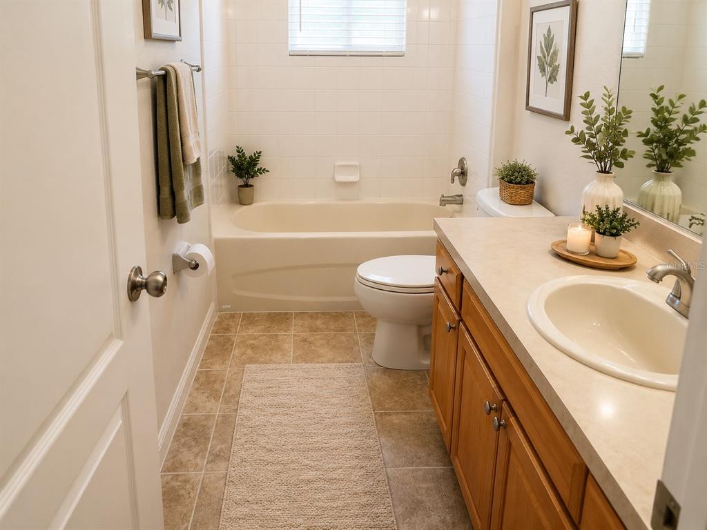 A bathroom features a vanity with a light countertop, a toilet, and a tub-shower combo — 101 BONITO WAY, POINCIANA, FL