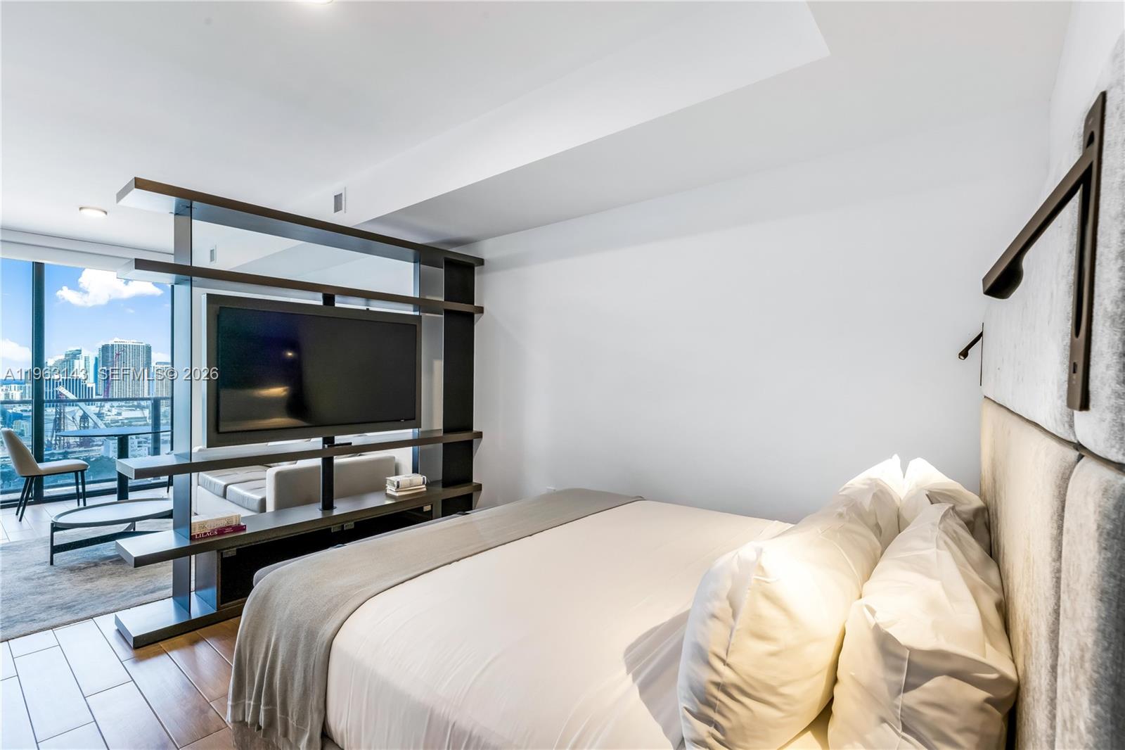 A bedroom features a bed, a television mounted on a room divider, and city views — 398 NE 5th St # 2205, Miami FL 33132, MIAMI, FL