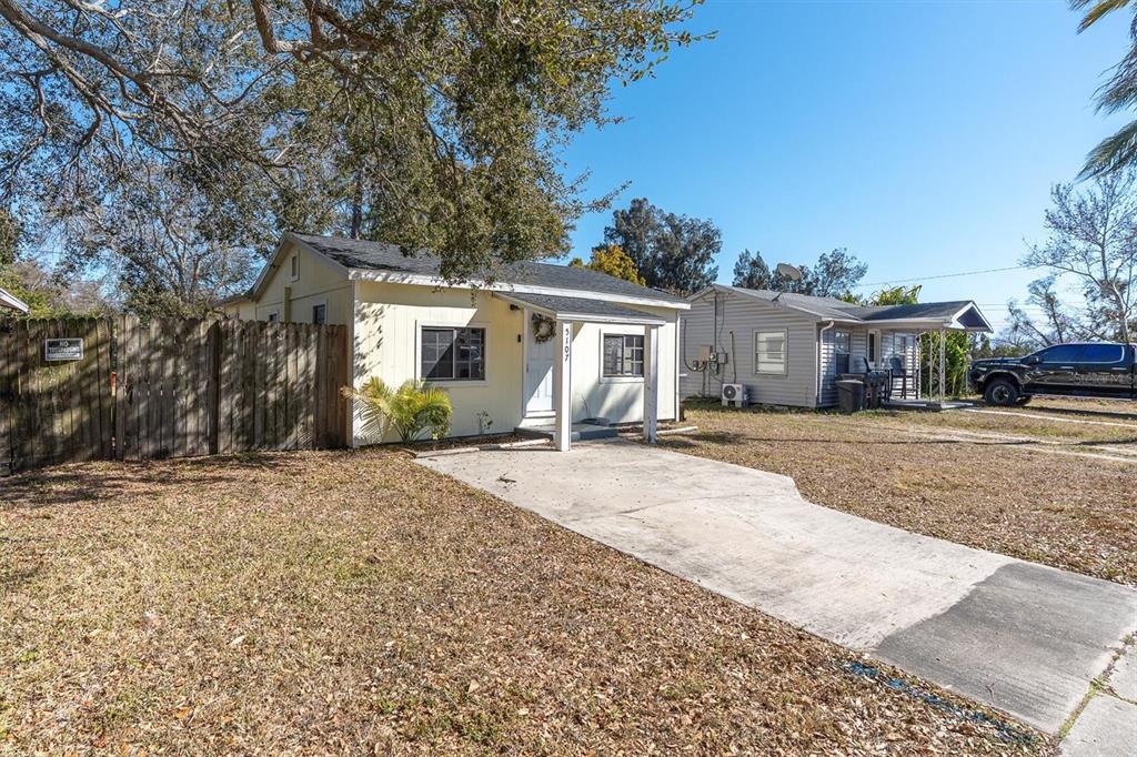 A yellow single-story house with a concrete driveway and a wooden fence on the left — 5107 37TH STREET N, ST PETERSBURG, FL