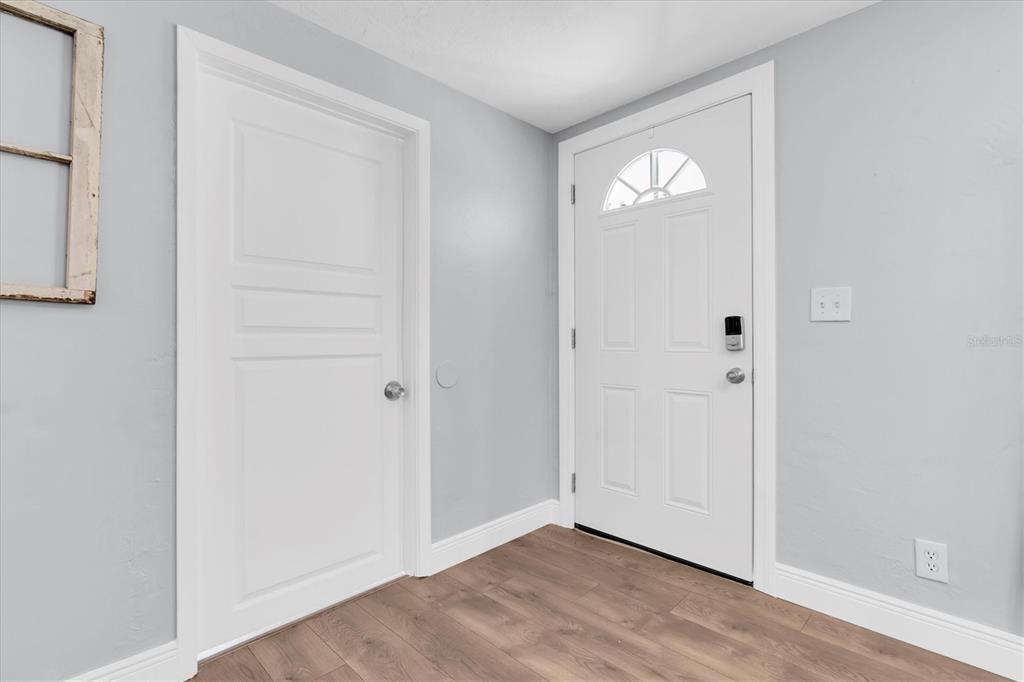An interior entryway features light gray walls, wood-look flooring, a white door, and a closet door — 5107 37TH STREET N, ST PETERSBURG, FL