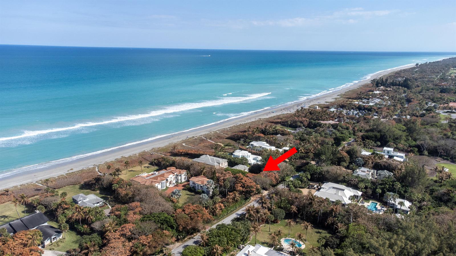 An aerial view shows a coastal neighborhood with luxury homes nestled among trees near the beach — 19 N Beach Road, Jupiter Island FL 33455, JUPITER ISLAND, FL
