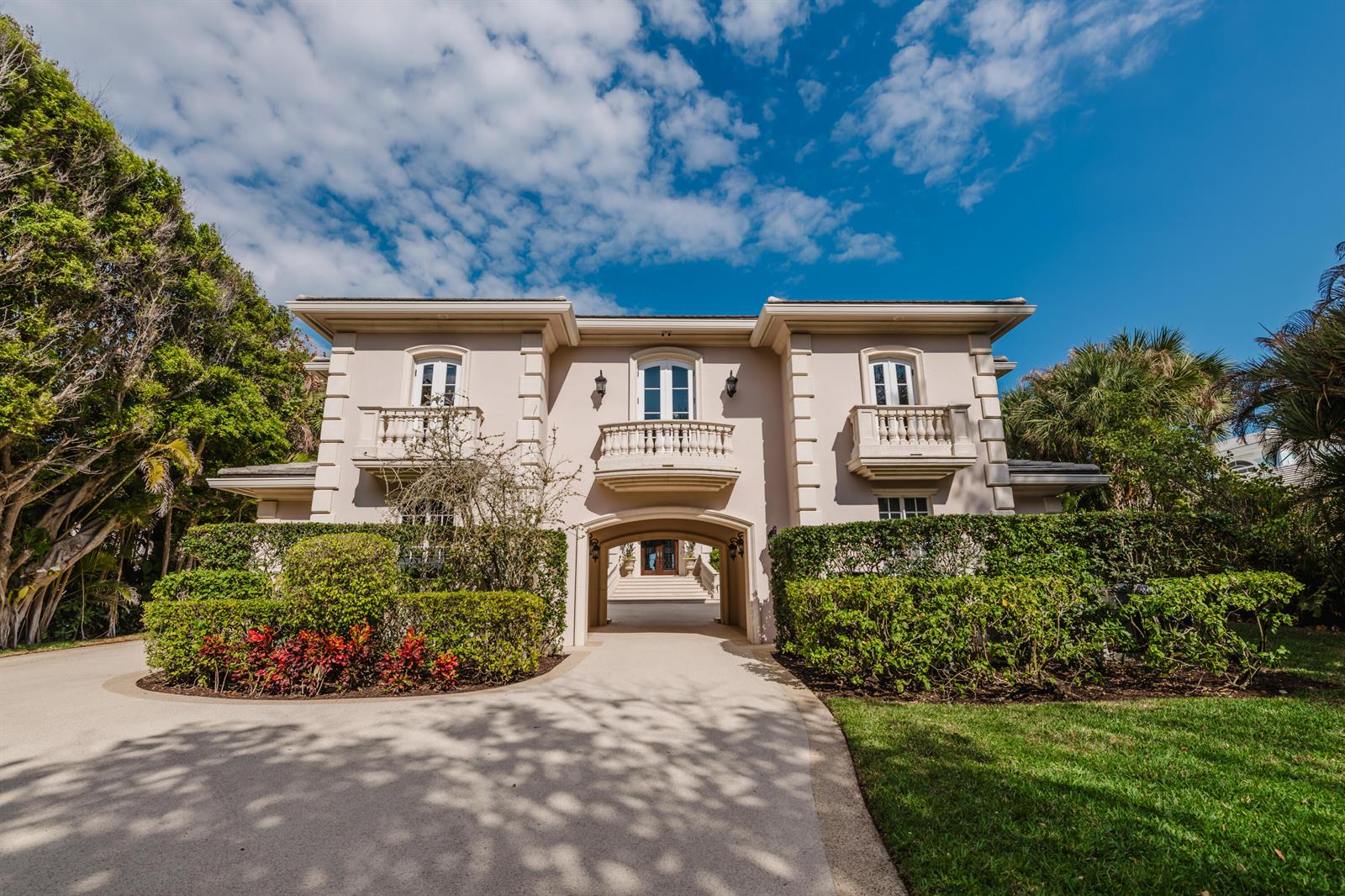 A two-story beige house with a central arched driveway and three small balconies — 19 N Beach Road, Jupiter Island FL 33455, JUPITER ISLAND, FL