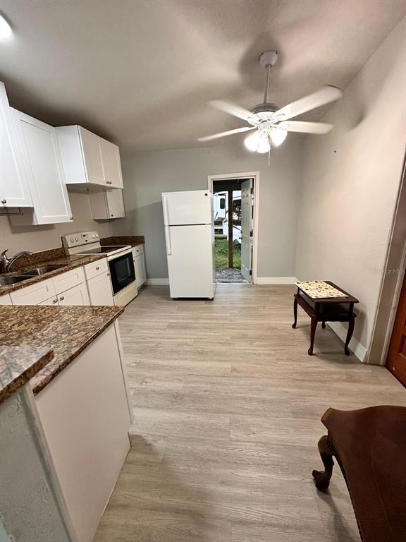 A kitchen with white cabinets, granite countertops, light wood-look flooring, and a ceiling fan — 3508 ORANOLE ROAD, ORLANDO, FL