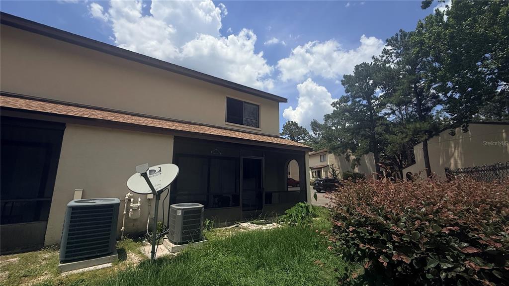 The exterior of a two-story townhouse features a screened patio, two air conditioning units, and a satellite dish — 2735 SW 35TH PLACE UNIT 1801, GAINESVILLE, FL
