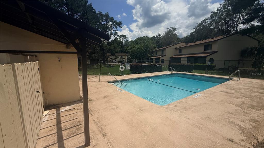 An outdoor swimming pool with a concrete deck and a covered structure in a residential complex — 2735 SW 35TH PLACE UNIT 1801, GAINESVILLE, FL