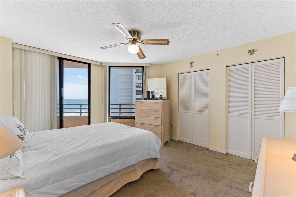A bedroom features a bed, a dresser, two closets, and a balcony overlooking the ocean — 3023 S ATLANTIC AVENUE UNIT 6060, DAYTONA BEACH, FL