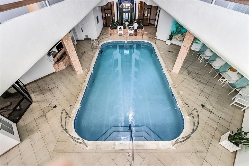 An indoor swimming pool with tiled flooring and lounge chairs is surrounded by white walls — 3023 S ATLANTIC AVENUE UNIT 6060, DAYTONA BEACH, FL