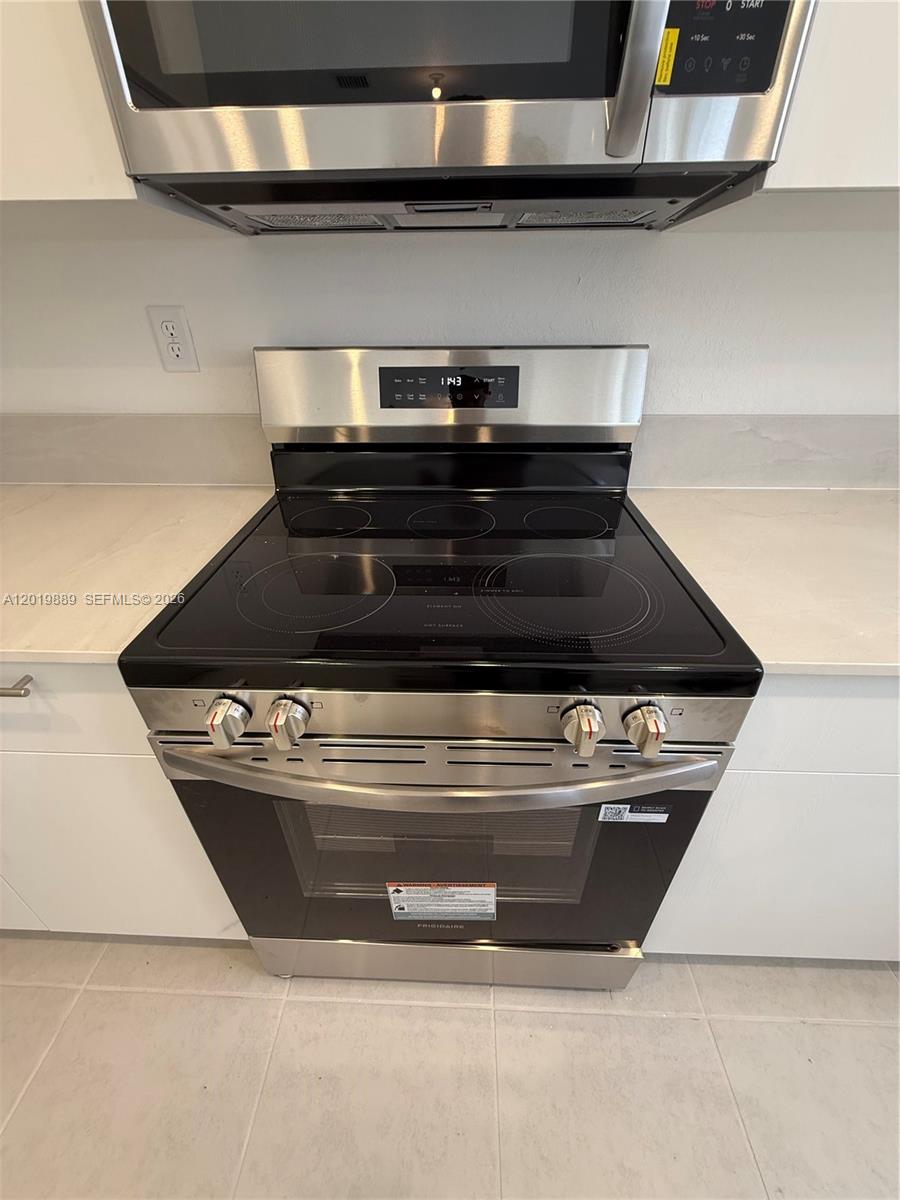 A stainless steel electric range and microwave are installed in a modern kitchen — HOMESTEAD, FL