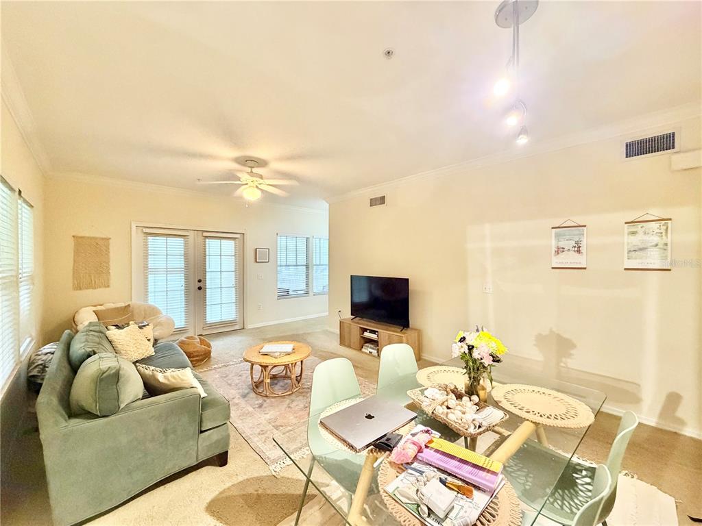 A living and dining area features a green sofa, glass table, and television on console — 9177 SW 52ND ROAD UNIT 203, GAINESVILLE, FL