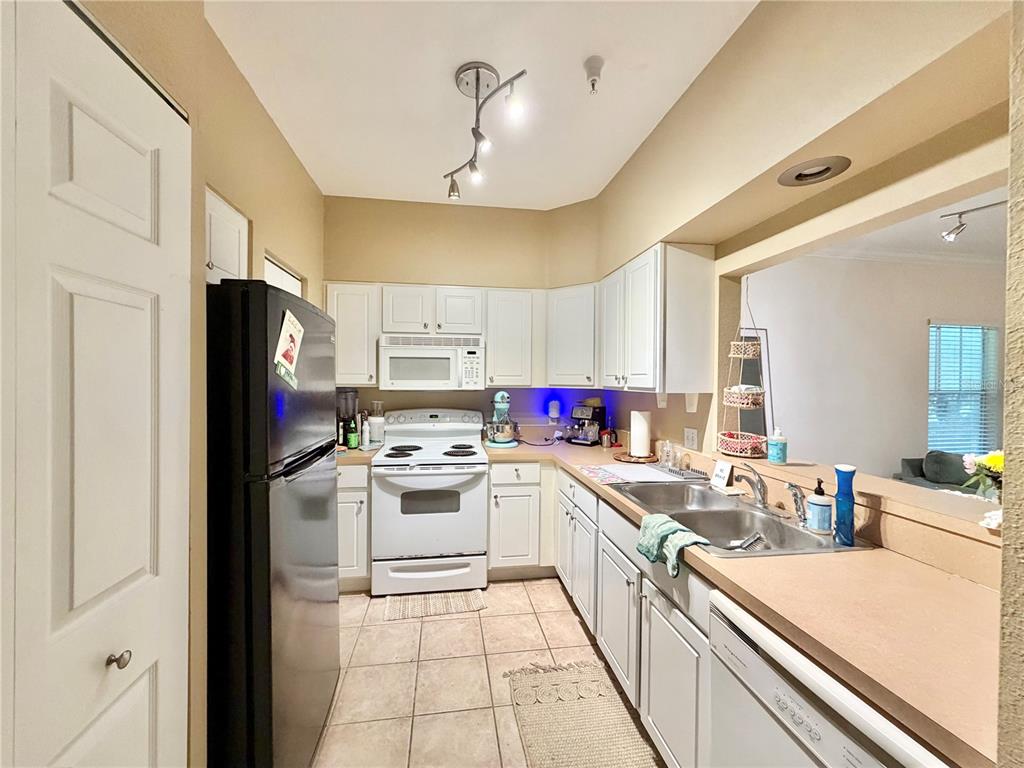 A kitchen features white cabinets, a black refrigerator, a white stove, and a double sink — 9177 SW 52ND ROAD UNIT 203, GAINESVILLE, FL