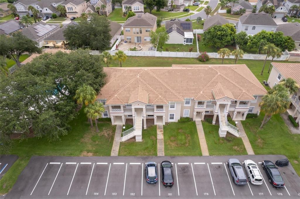 An aerial view shows a multi-unit residential building with a tiled roof and parking lot — 13403 FAIRWAY GLEN DRIVE UNIT 203, ORLANDO, FL