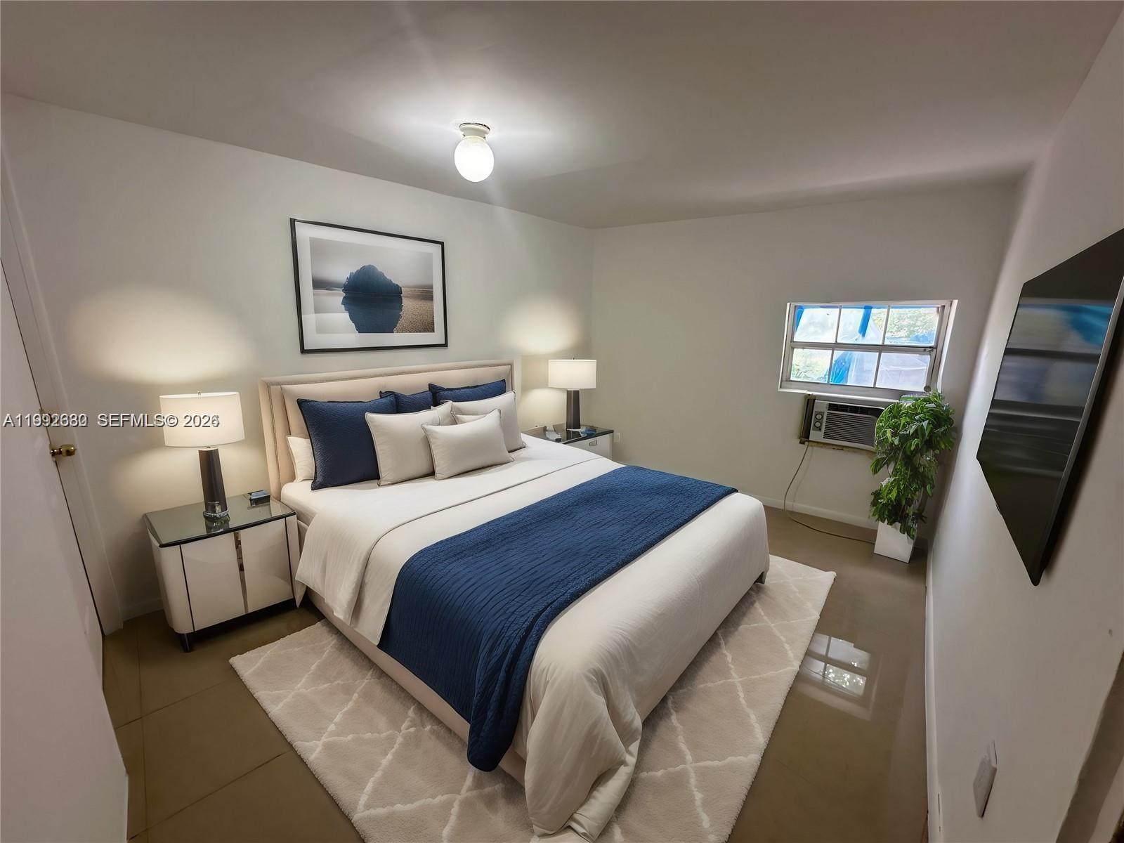 A bedroom features a bed with blue bedding, two nightstands, a rug, and a wall-mounted television — 1572 NE 149th St # C, Miami FL 33161, MIAMI, FL
