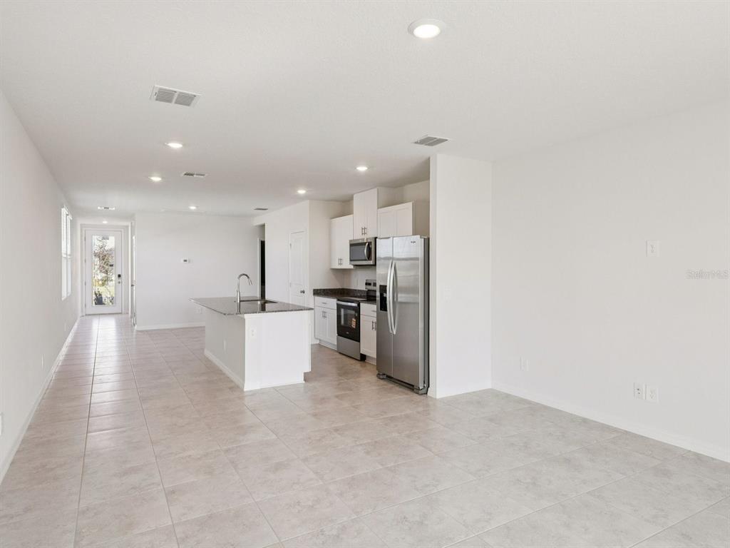 A modern kitchen features white cabinets, stainless steel appliances, and a granite-topped island — 5313 WILLOW CREEK, HAINES CITY, FL