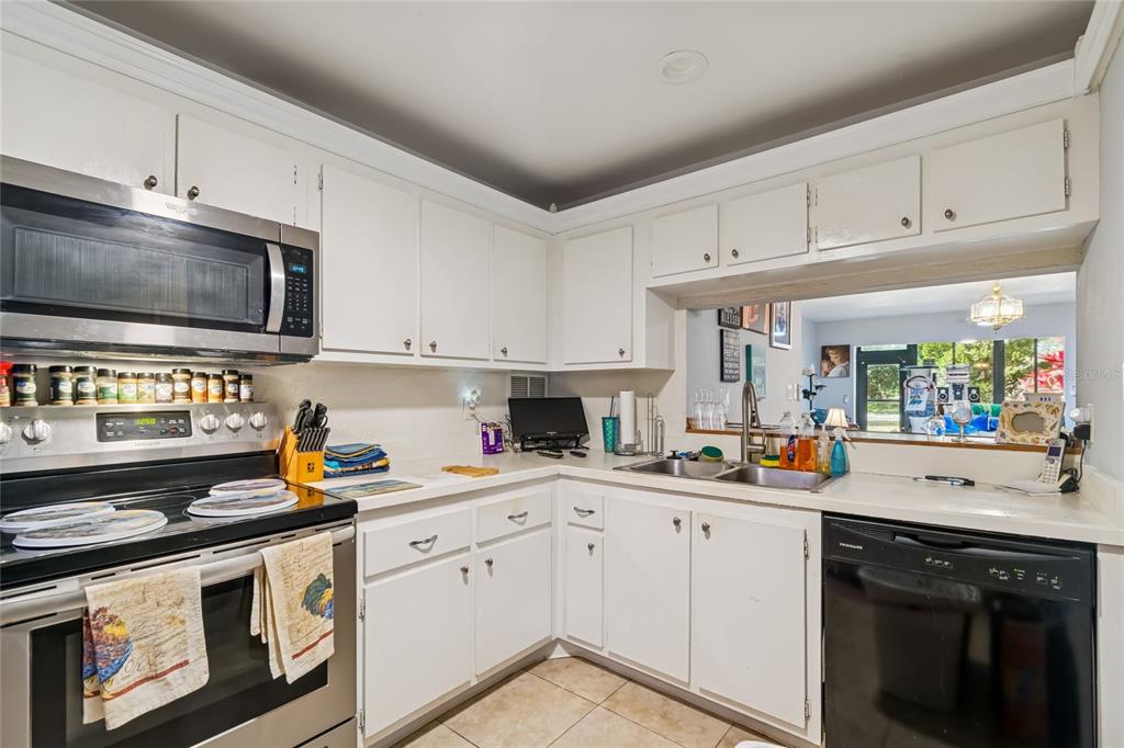 A kitchen with white cabinets, stainless steel appliances, and a pass-through window to another room — 2679 SABAL SPRINGS CIRCLE UNIT 102, CLEARWATER, FL