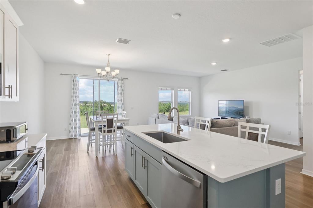 A kitchen island with a sink overlooks an open-concept dining area and living room — 2326 GOLD DUST DRIVE, MINNEOLA, FL