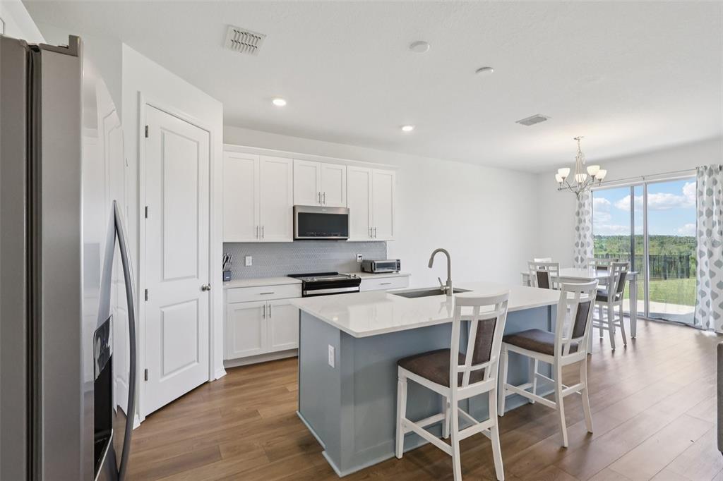 A kitchen features white cabinets, a blue island with bar seating, and wood-look flooring — 2326 GOLD DUST DRIVE, MINNEOLA, FL