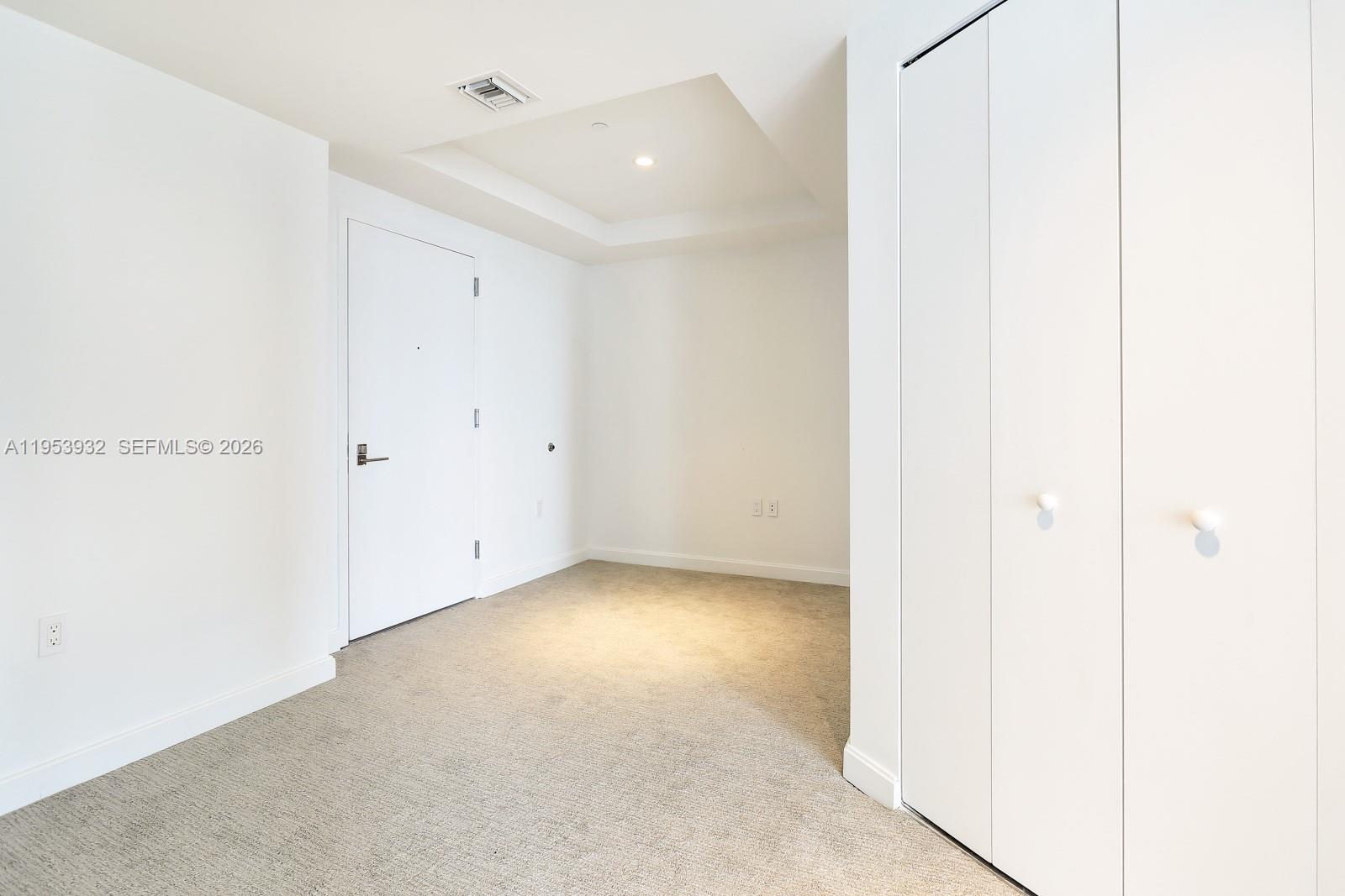 An empty room features white walls, beige carpeting, a recessed ceiling, and white closet doors — 45 SW 9th St # 1806, Miami FL 33130, MIAMI, FL
