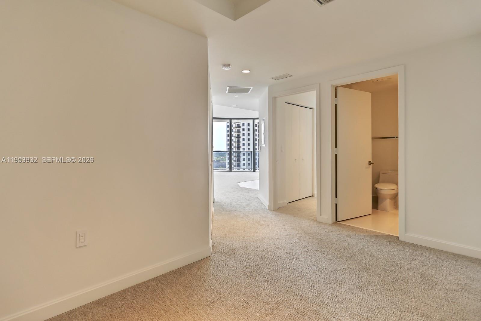 A carpeted hallway leads to a living area with floor-to-ceiling windows and a bathroom — 45 SW 9th St # 1806, Miami FL 33130, MIAMI, FL