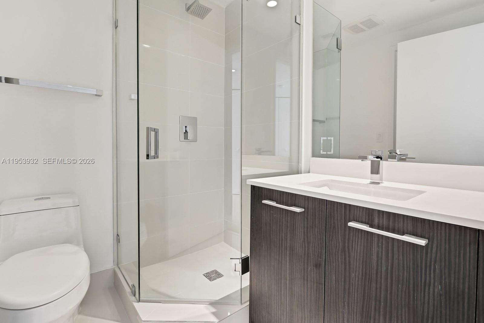 A modern bathroom features a glass-enclosed shower, a white toilet, and a dark wood vanity — 45 SW 9th St # 1806, Miami FL 33130, MIAMI, FL