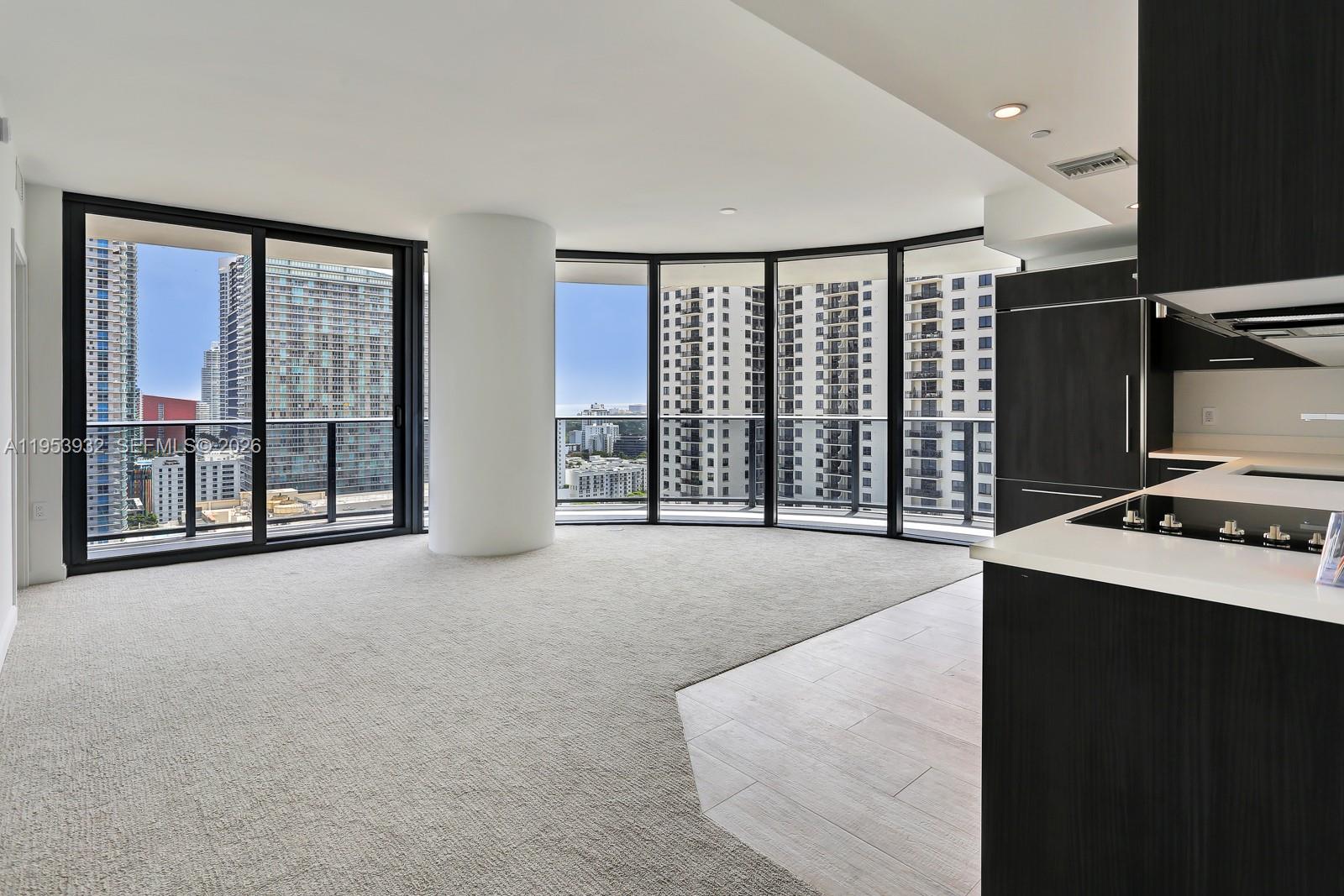An open-concept living area features carpeted flooring, a central structural column, and floor-to-ceiling windows — 45 SW 9th St # 1806, Miami FL 33130, MIAMI, FL