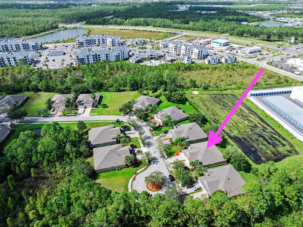 An aerial view shows a residential neighborhood with houses, a pond, and nearby apartment buildings — 188 MENDOZA CIRCLE, DAYTONA BEACH, FL