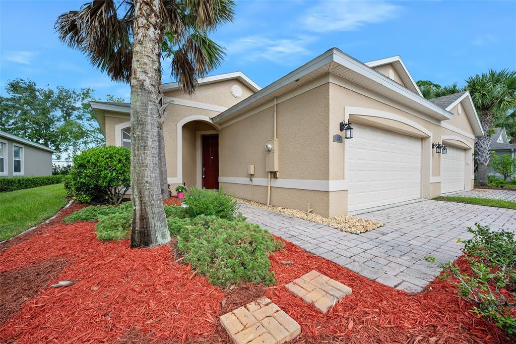 A single-story tan stucco house with a two-car garage and a paved driveway — 188 MENDOZA CIRCLE, DAYTONA BEACH, FL