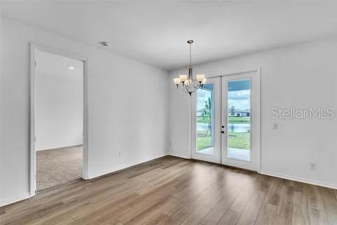 A dining area with wood-look flooring, a chandelier, and glass doors leading to a backyard — 453 ARCHWAY PLACE, ST CLOUD, FL