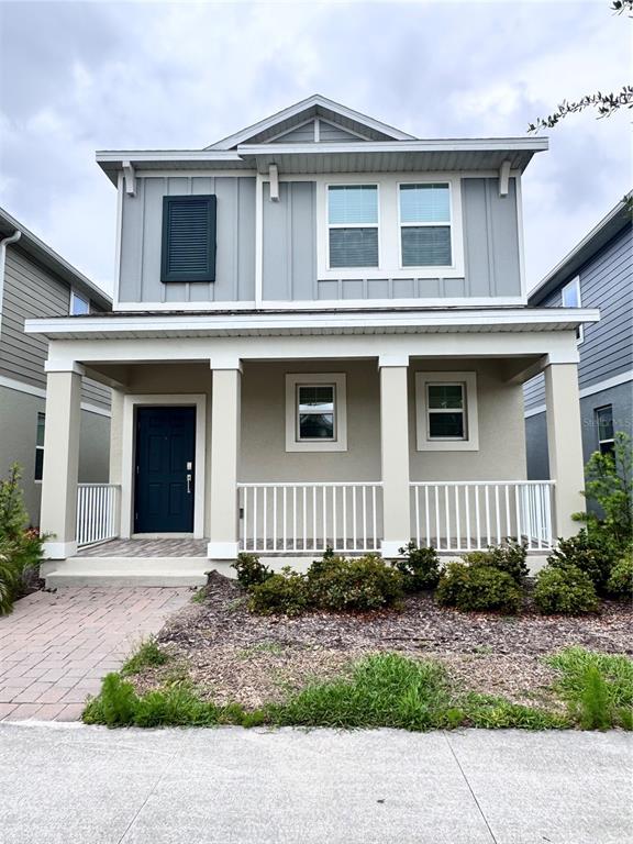 A two-story house with a covered front porch, gray siding, and a dark blue door — 1563 CROSS PRAIRIE PARKWAY, KISSIMMEE, FL