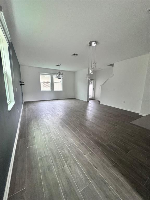 An open-concept living area features gray wood-look tile flooring and two modern pendant light fixtures — 1563 CROSS PRAIRIE PARKWAY, KISSIMMEE, FL
