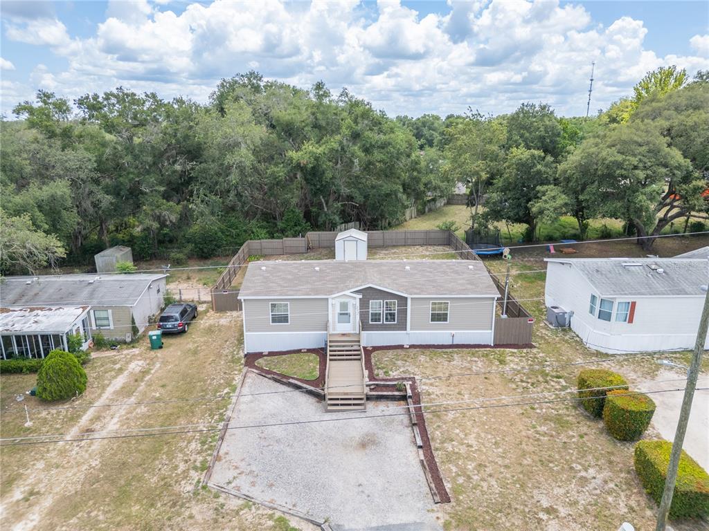 An aerial view shows a manufactured home with a gravel driveway and a fenced backyard — 242 SKYLINE DRIVE, LADY LAKE, FL
