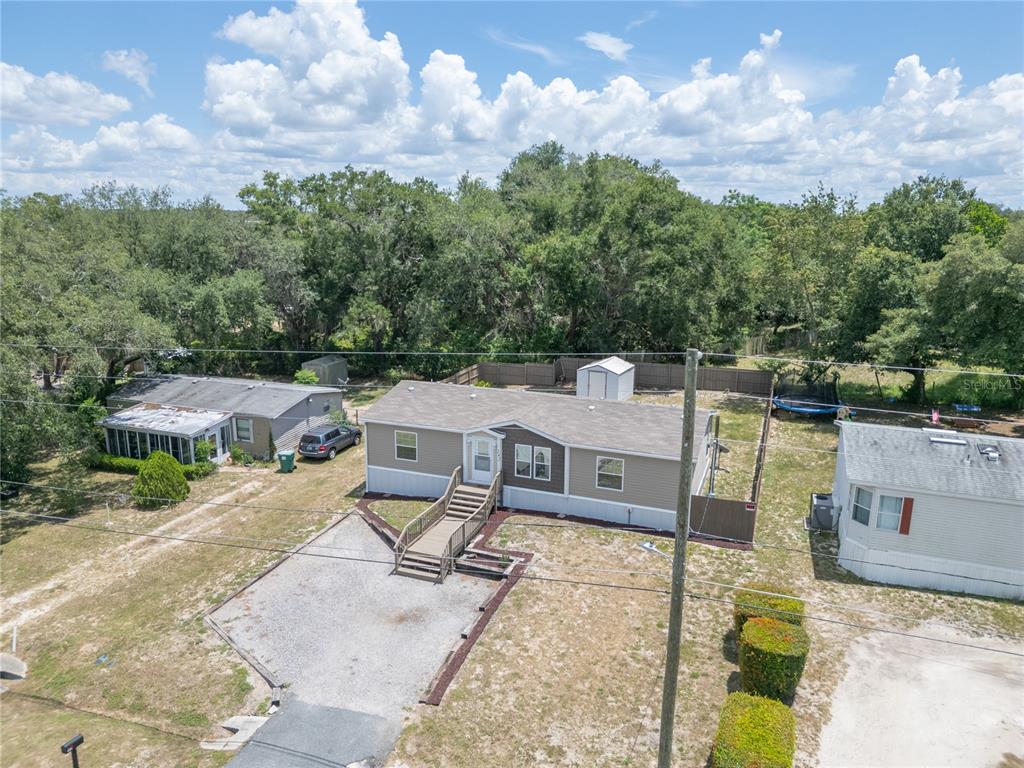 An aerial view shows a single-story manufactured home with a gravel driveway and fenced yard — 242 SKYLINE DRIVE, LADY LAKE, FL