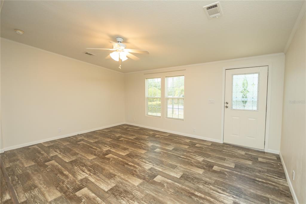 An empty room features light-colored walls, a ceiling fan, and wood-look flooring — 242 SKYLINE DRIVE, LADY LAKE, FL