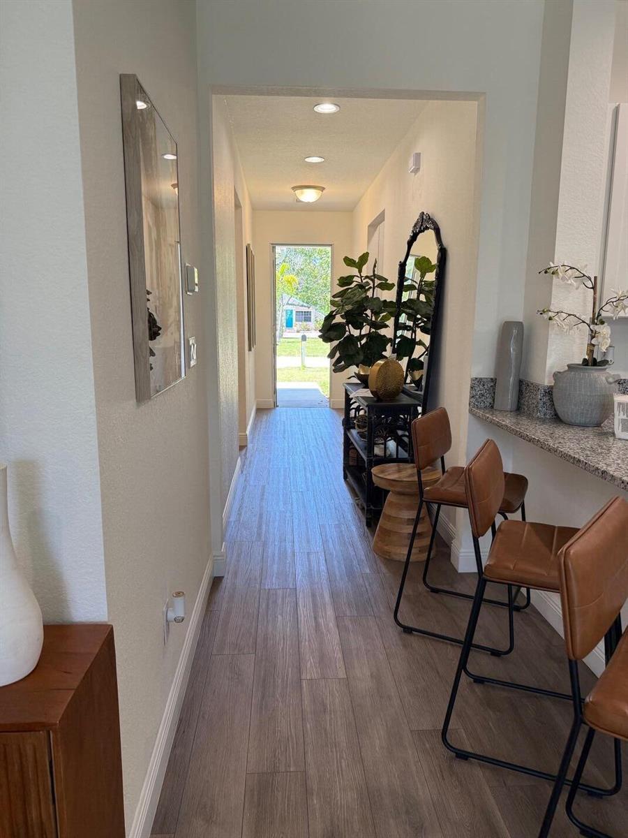 A hallway with wood-look tile flooring leads to an open doorway showing an outdoor view — 341 Oak Alley, Delray Beach FL 33444, DELRAY BEACH, FL