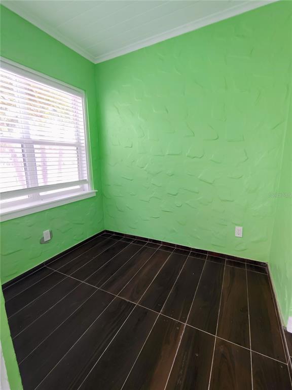 A small room features bright green textured walls, dark wood-look tile flooring, and a window — 115 145TH AVENUE E UNIT 3, MADEIRA BEACH, FL