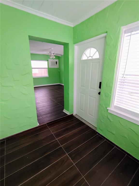 An entryway with bright green textured walls, dark wood-look flooring, and a white front door — 115 145TH AVENUE E UNIT 3, MADEIRA BEACH, FL