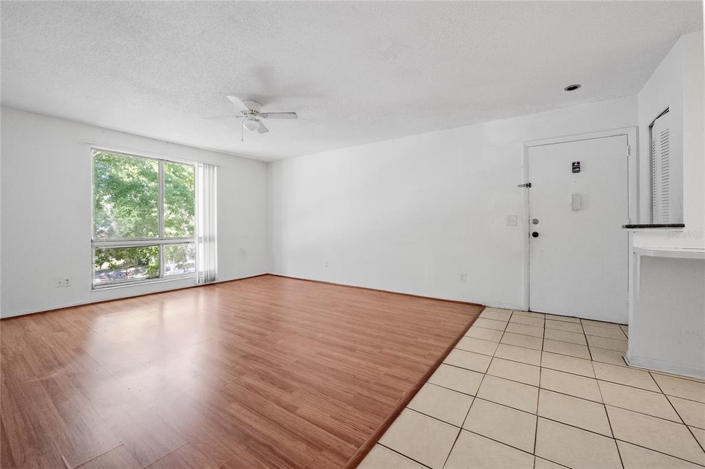 A living room with wood-look flooring, white walls, a ceiling fan, and a tiled entryway — 1700 SW 16TH COURT UNIT J24, GAINESVILLE, FL