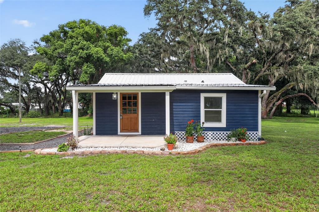 A small blue house with a white metal roof and a covered front porch — 4746 LAMAR ROAD, ZEPHYRHILLS, FL