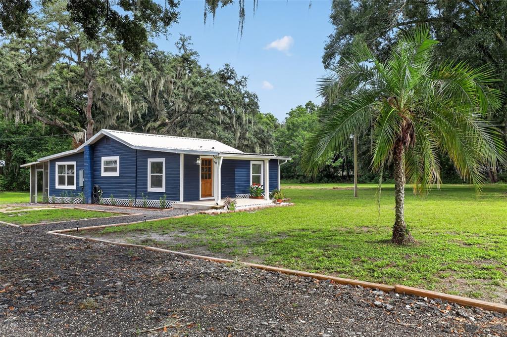 A blue single-story house with a white metal roof sits on a grassy lot — 4746 LAMAR ROAD, ZEPHYRHILLS, FL