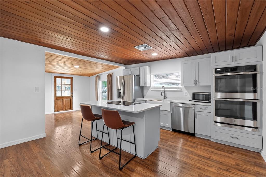 A kitchen with a wood-paneled ceiling, white cabinets, stainless steel appliances, and a center island — 4746 LAMAR ROAD, ZEPHYRHILLS, FL