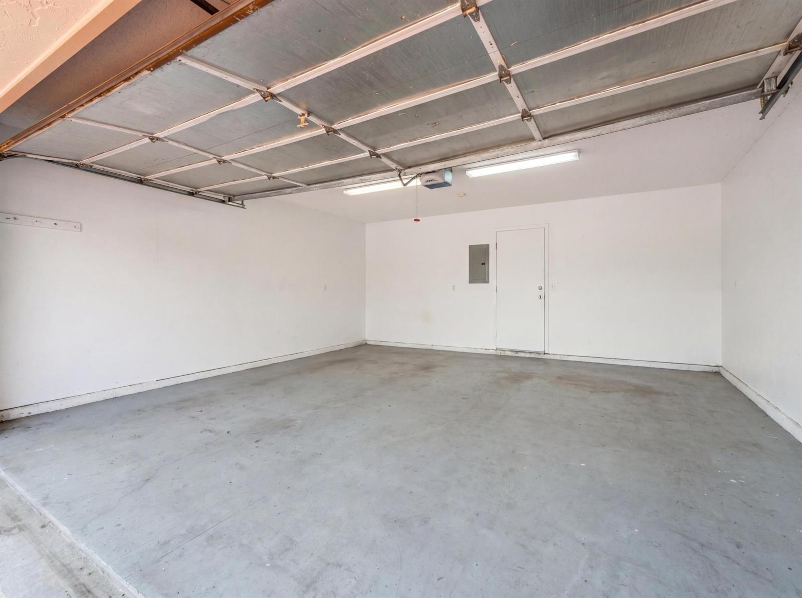 An empty garage with white walls, a gray concrete floor, and a metal door — 8521 Leeway Lane, Boynton Beach FL 33436, BOYNTON BEACH, FL