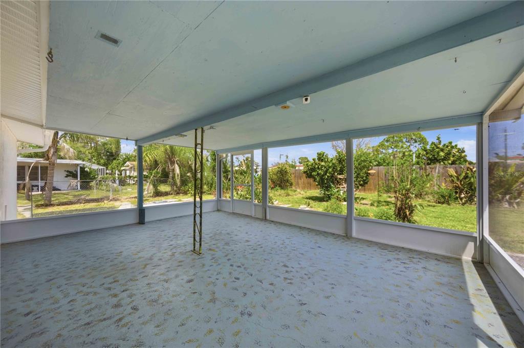 A screened-in porch with a blue painted ceiling and floor overlooking a grassy backyard — 917 CHURCH STREET, VENICE, FL