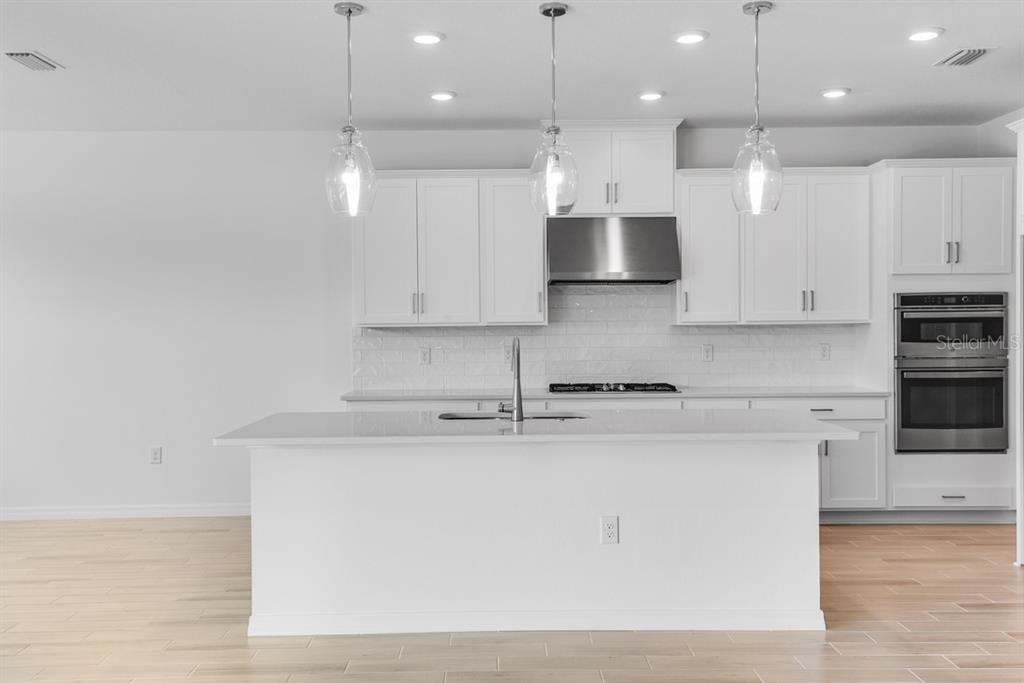 A modern kitchen features white cabinets, a central island with a sink, and light flooring — 846 JUNONIA BOULEVARD, NEW SMYRNA BEACH, FL