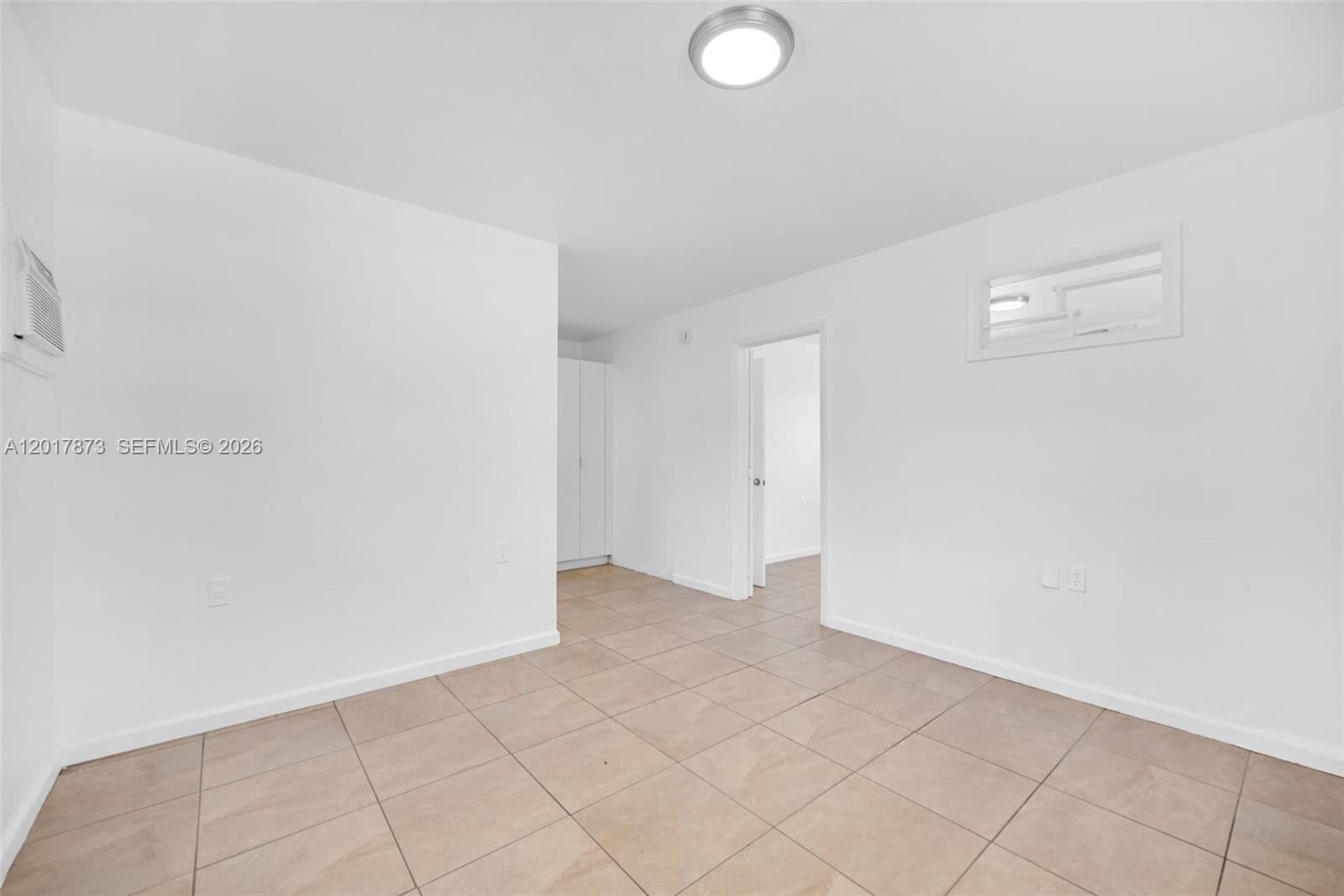 An empty room with white walls, tile flooring, a ceiling light, and a doorway — 567-3 NW 90th St, El Portal FL 33150, EL PORTAL, FL