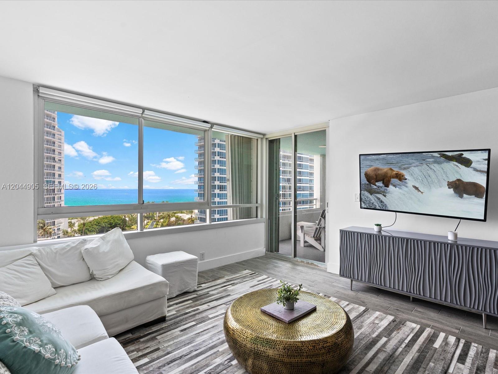A living room features a white sofa, a gold coffee table, and ocean views — 400 S Pointe Dr # 1102, Miami Beach FL 33139, MIAMI BEACH, FL